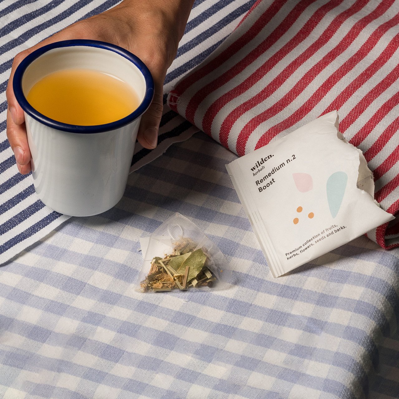 Simple cup of herbal organic infusion hold by a hand with line-pattern fabrics